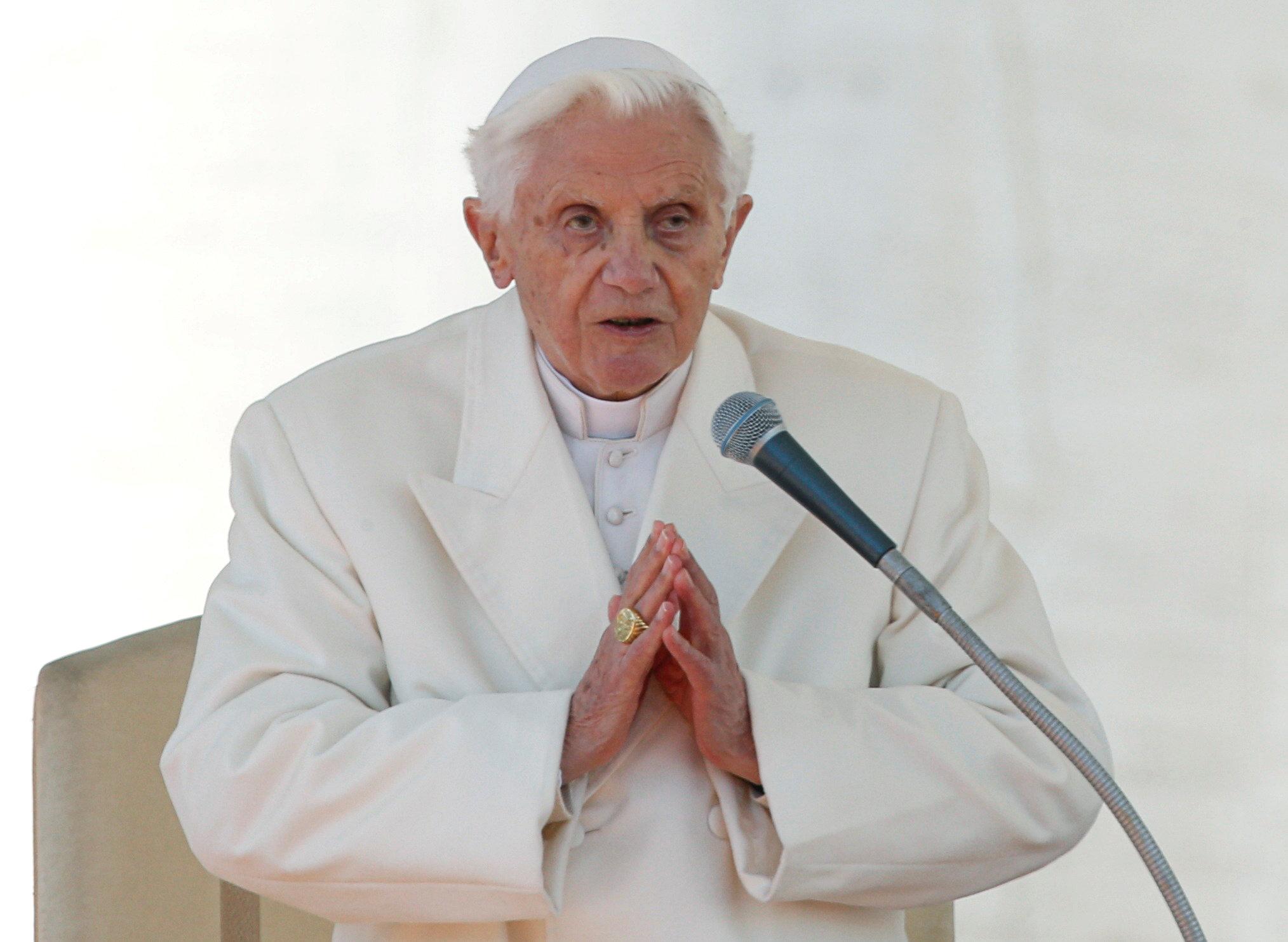 Pope benedict wearing a white church outfit and giving a speech on mic