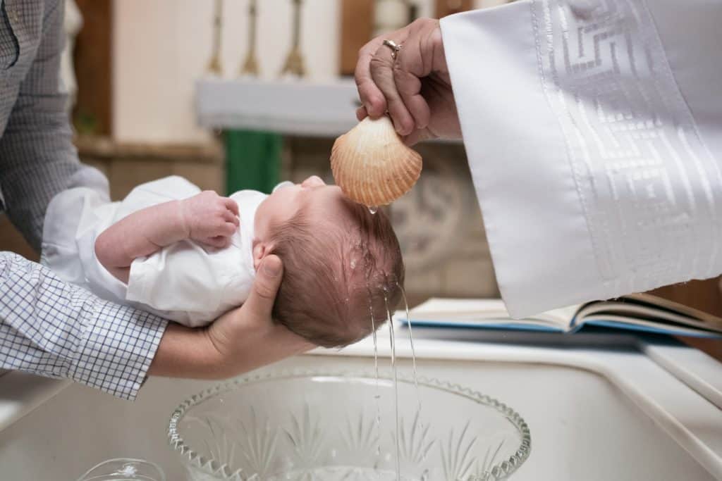 A priest pouring water over the baby's head for baptism