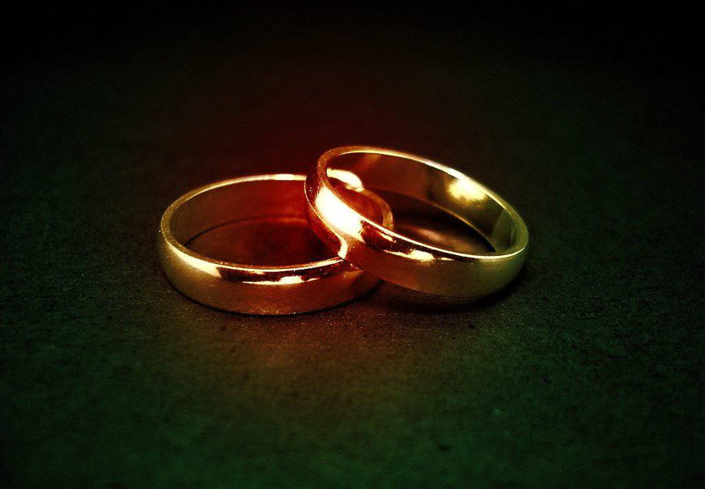 Two golden colored wedding rings on a black surface