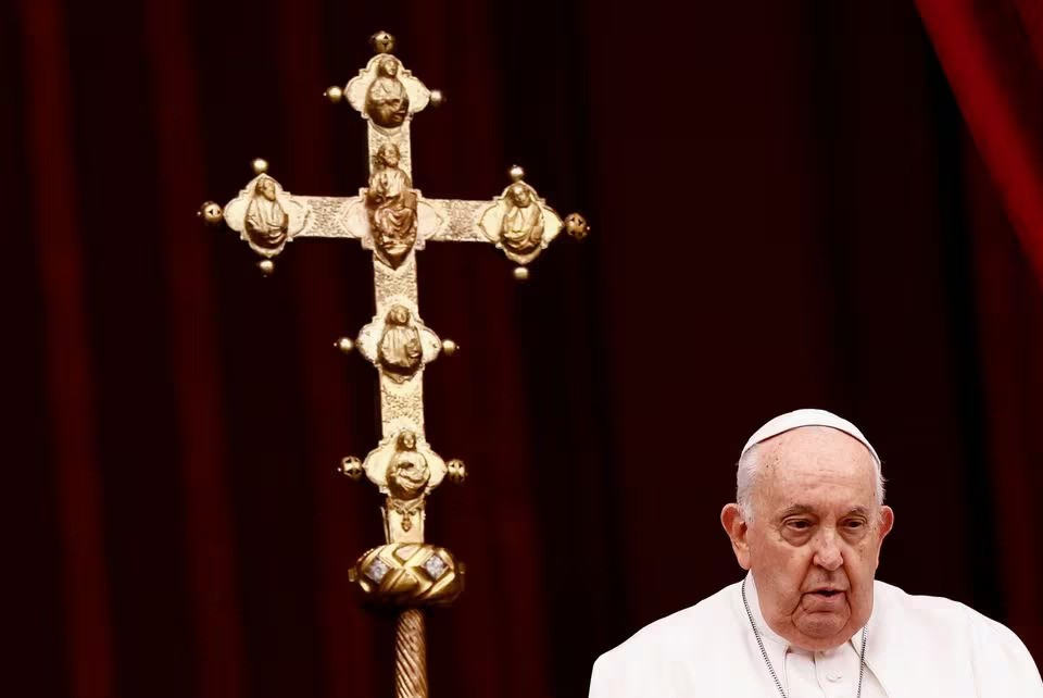 Pope Francis standing by a golden cross during his speech